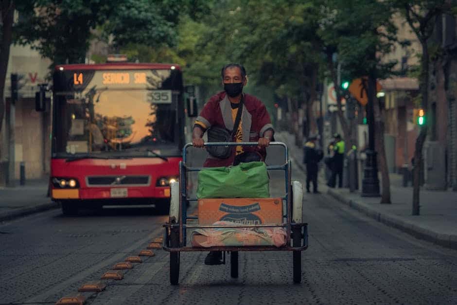 A man rides a tricycle loaded with goods on a busy street in Ciudad de México, CDMX.