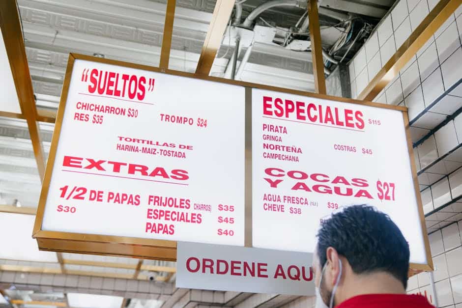 Overhead illuminated menu sign with various food options in a Mexican restaurant setting.