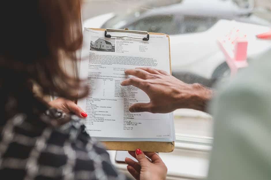 Real estate agent discussing property details with client using a clipboard indoors.