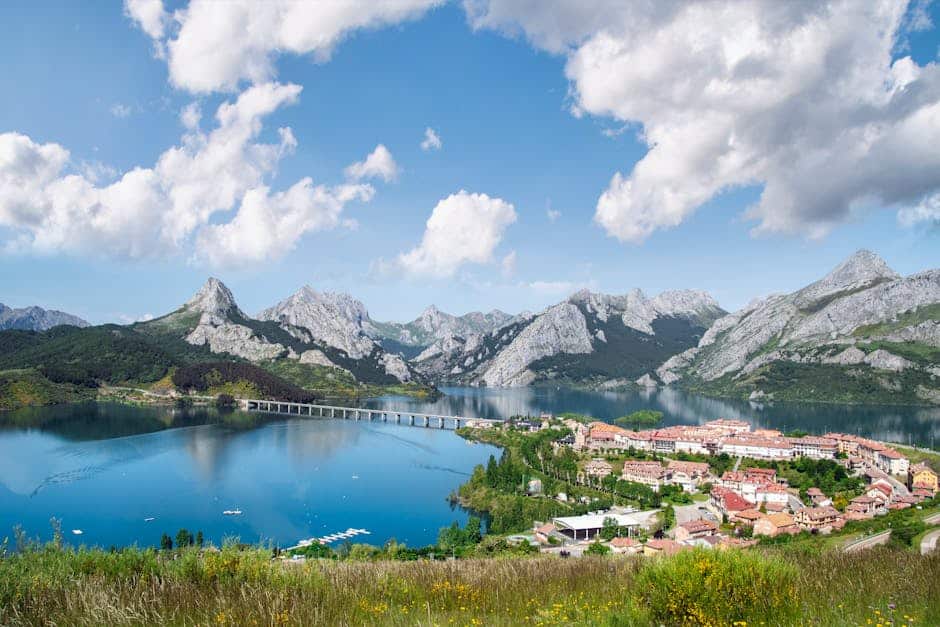 Picturesque landscape of Riaño village, lake, and mountains under a vibrant sky in Castilla y León, Spain.