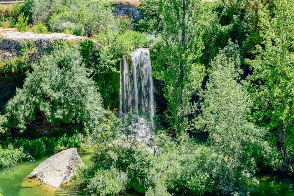 Stunning natural waterfall surrounded by lush greenery in La Orden, Spain.