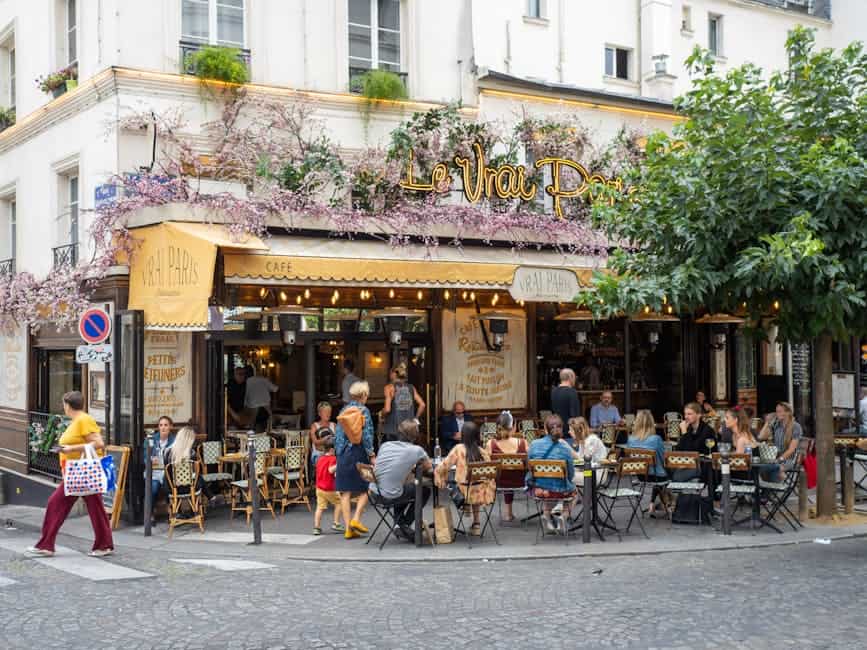 Outdoor view of Le Vrai Paris bistro in Montmartre, Paris, with people dining and vibrant atmosphere.