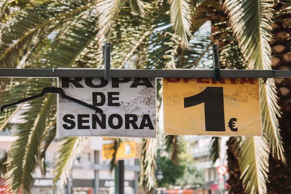 Outdoor street market signs in Valencia, Spain, with palm leaves in the background.