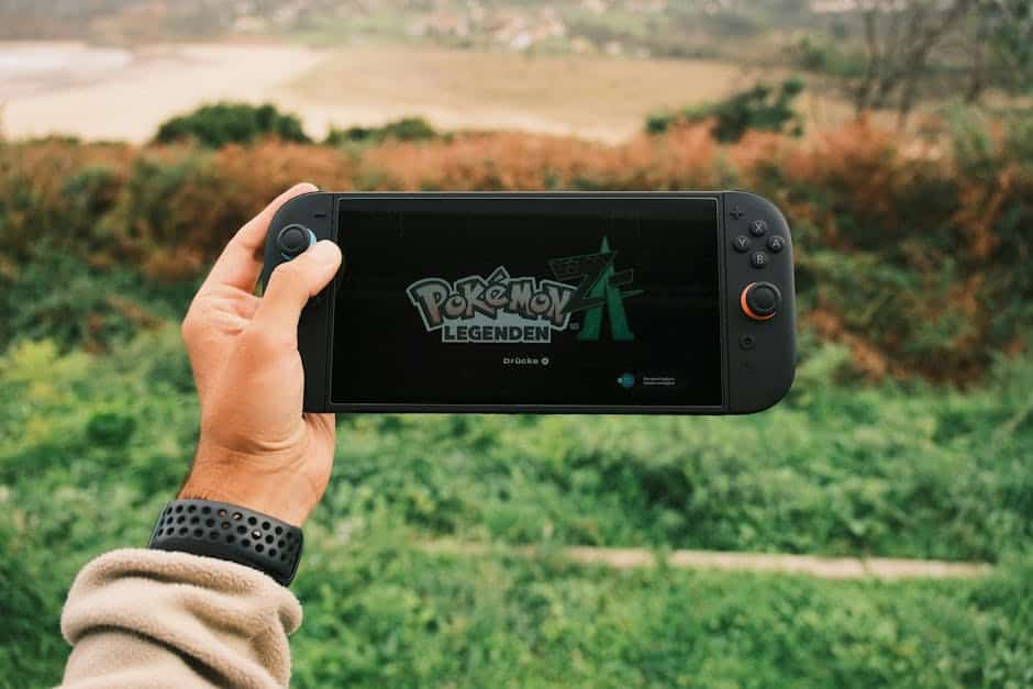 A person holds a handheld gaming device outdoors with Pokémon Legends on screen.